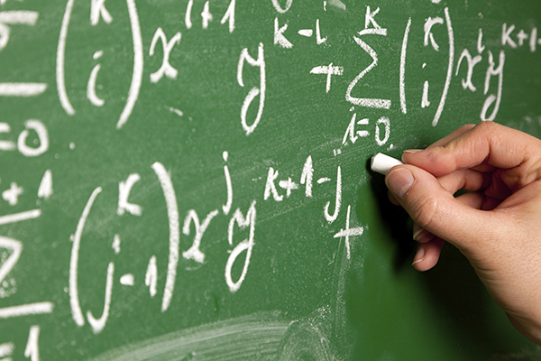 Professor writing mathematical equation on blackboard